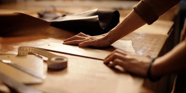 Hands working on a sewing pattern with measuring tape.