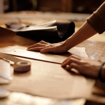 Person measuring fabric with a ruler on a table.