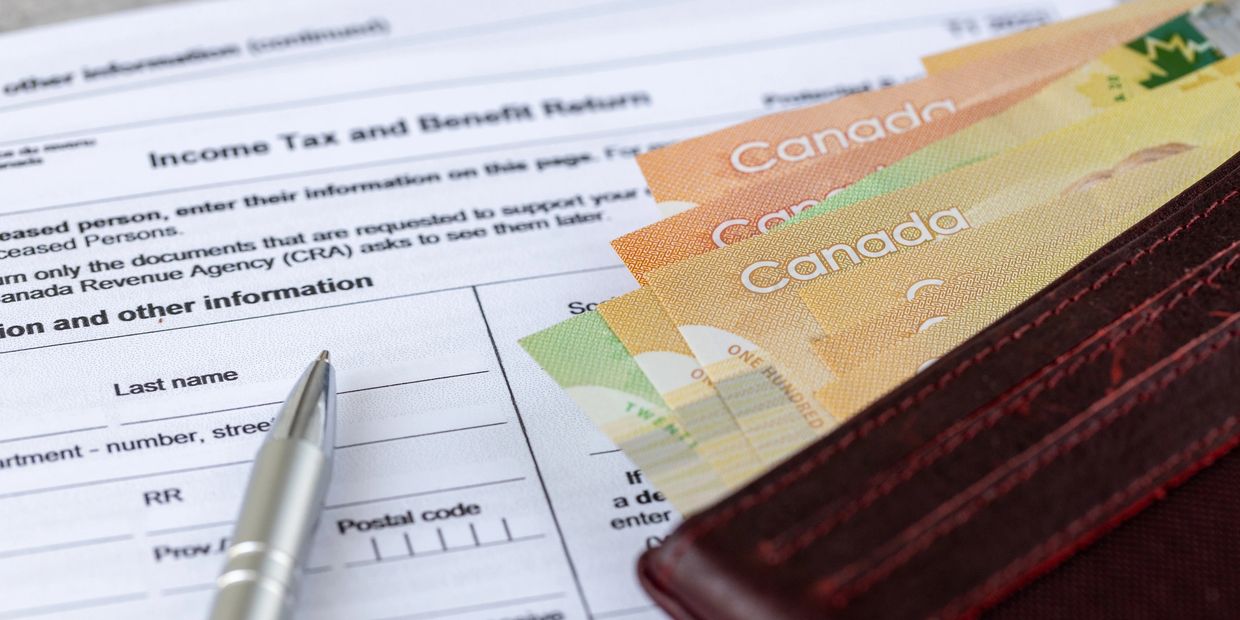 Canadian money and a pen on an income tax return form.