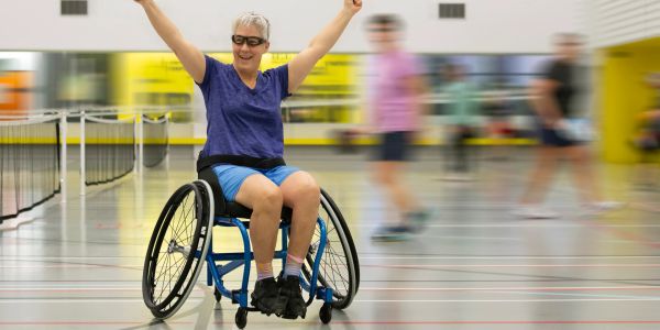 Woman in a wheelchair celebrating in a sports hall.