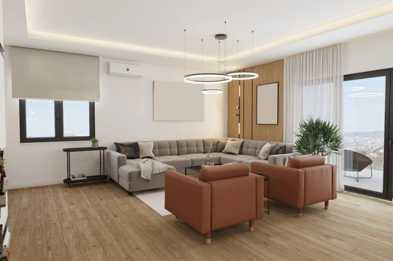 A beautifully designed modern living room featuring a spacious sofa, sleek armchairs, and natural lighting. The elegant decor creates a warm and inviting atmosphere, perfect for relaxation or hosting guests.