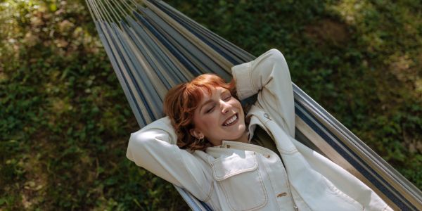 A woman relaxes on a hammock outdoors.