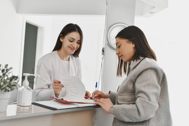 Organized Female Receptionist Giving Patient Discharge Paperwork and Scheduling Follow-Up Appointment