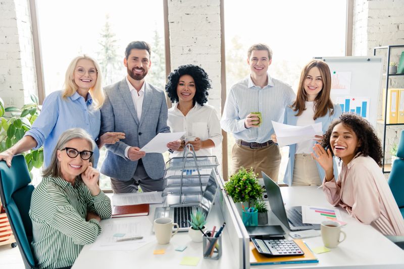 Group of coworkers teaming up in a bright office, showcasing teamwork and diversity