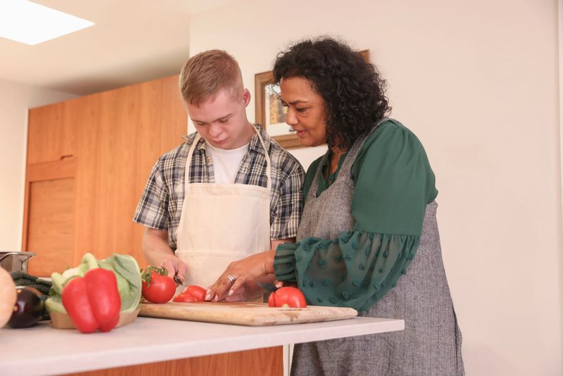 Mature mother and adult son with down syndrome cooking together at home