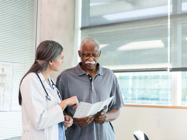 Doctor explaining medical information to an elderly man in a clinic.