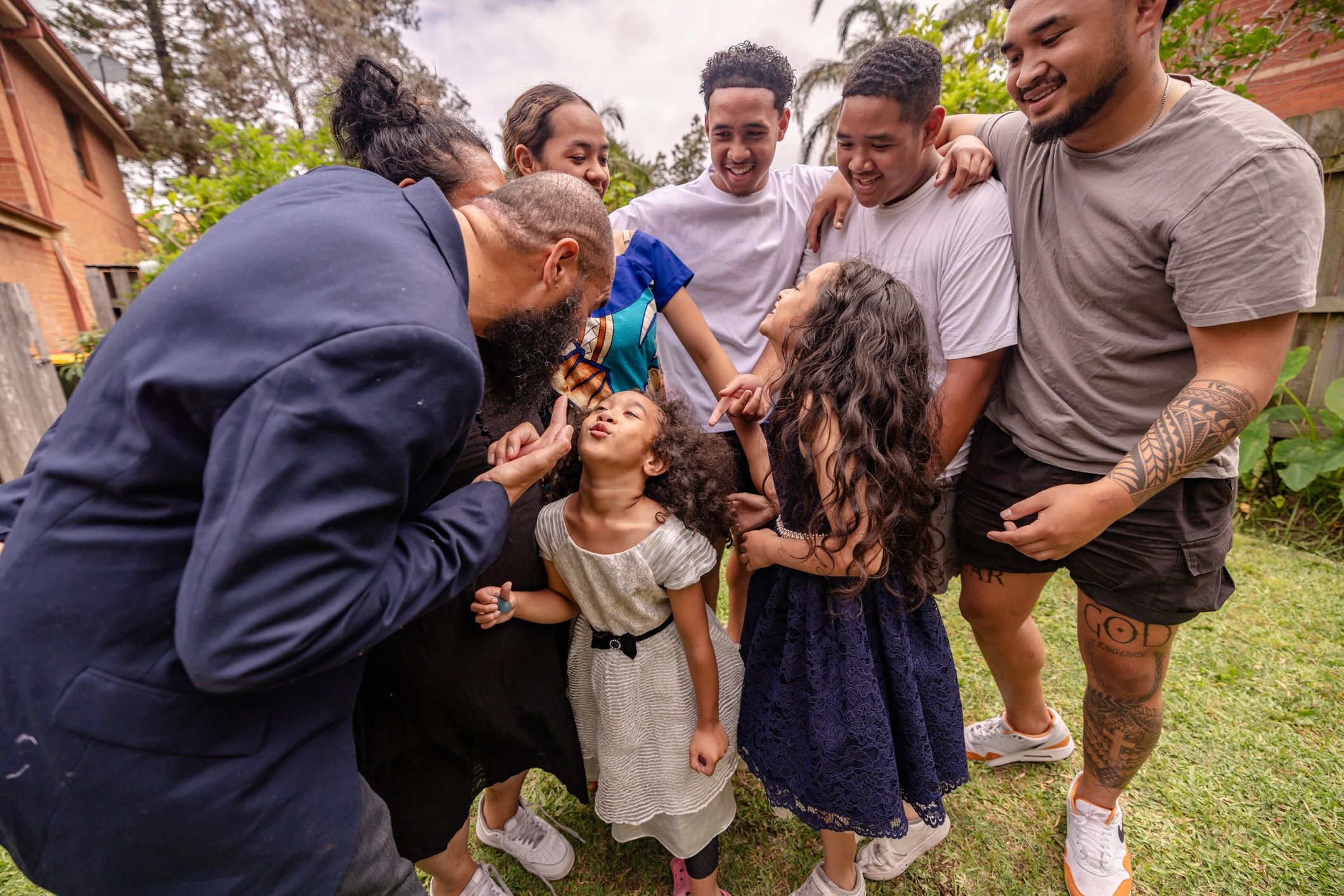 A joyful family moment with adults and children sharing smiles and laughter outdoors.