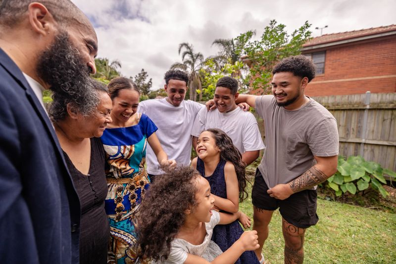 A Tongan family shares moments of laughter and connection in a Sydney backyard, reflecting their rich culture and strong bonds during a traditional gathering.