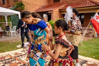 Two girls in traditional Polynesian attire performing a dance outdoors.