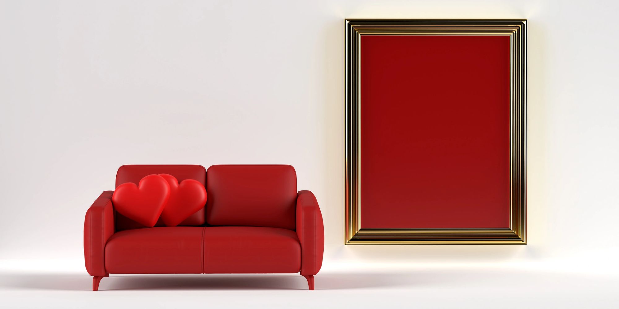 Red sofa with two heart pillows, next to a red framed picture.