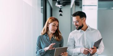 Man reviewing finance reports at a desk with laptop and documents.