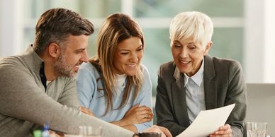Three professionals discussing documents in a bright office.