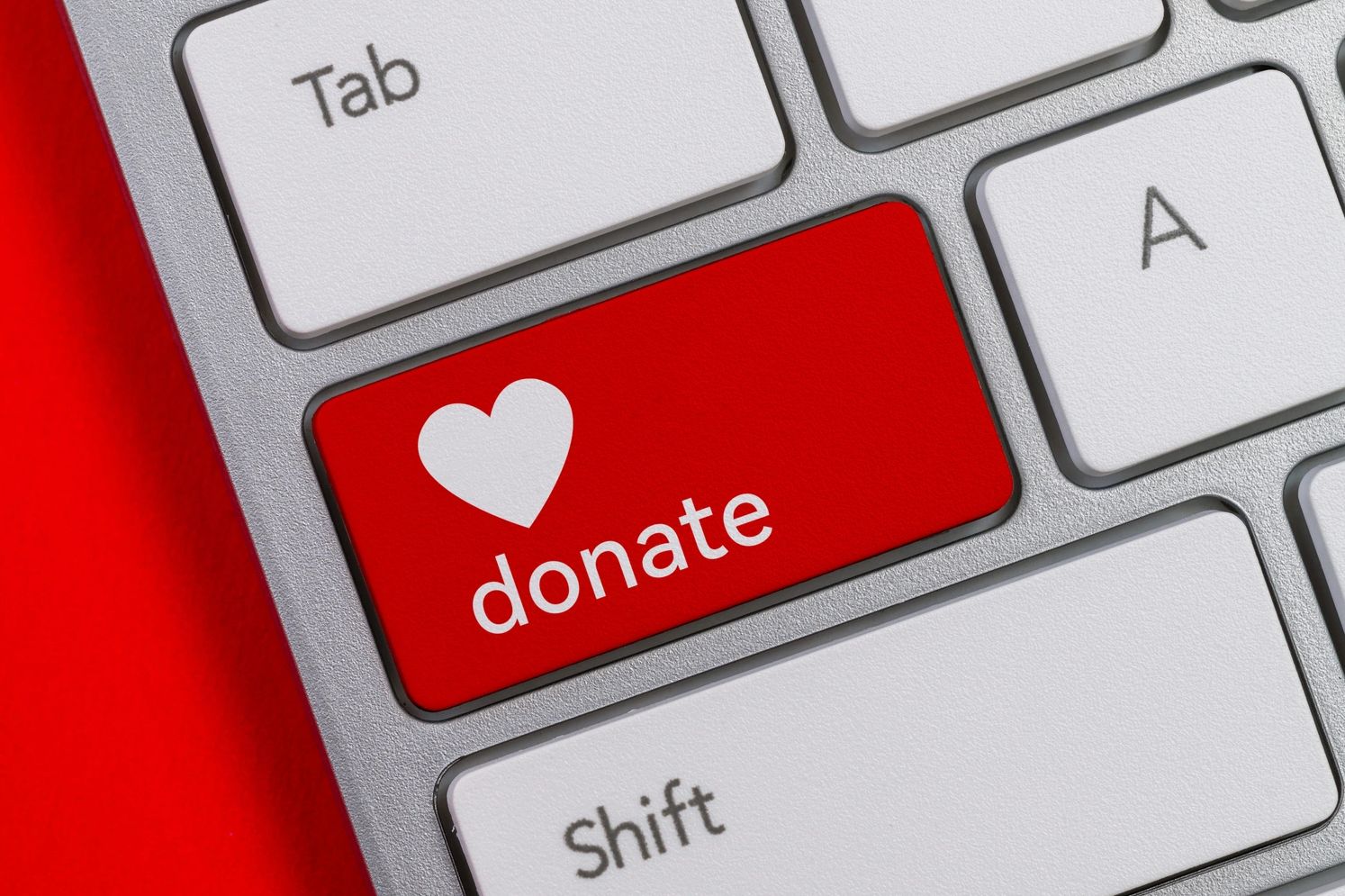 Red donate key on a keyboard with a heart symbol.