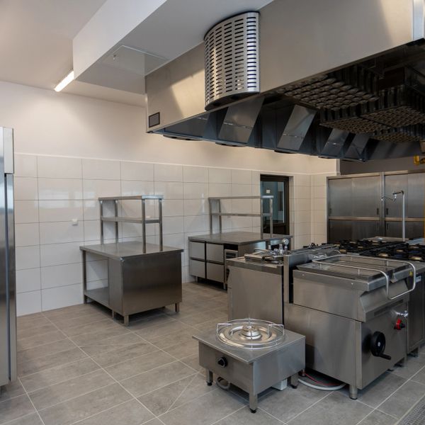 A clean, modern commercial kitchen with stainless steel appliances and workstations.