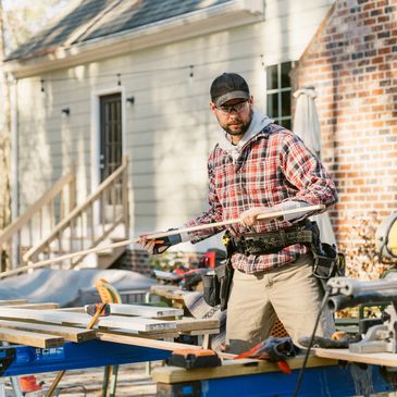 Construction person with wood outside of house