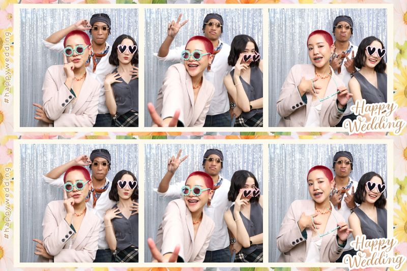 Group of LGBTQIA+ friends having fun posing with a photo booth at a wedding.