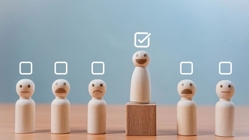 Employee Performance Evaluation and HR Selection. A smiling wooden figure stands elevated on a block with a checkmark. symbolizing selection, leadership, excellence, and customer satisfaction.