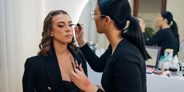Makeup artist applying mascara on a woman's eyelashes.
