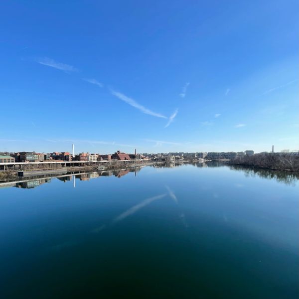 Calm river with clear sky and cityscape reflection.