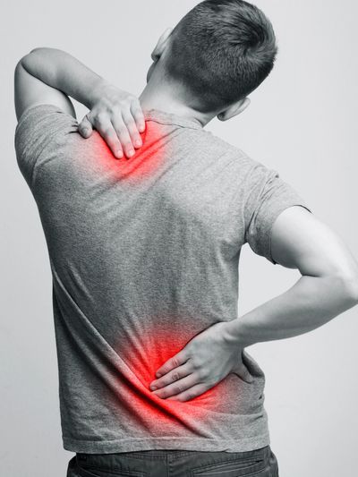 Man holding his neck and lower back in pain with red highlights.