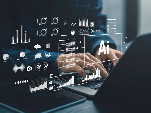 Person typing on laptop with AI and data analytics graphics overlay.