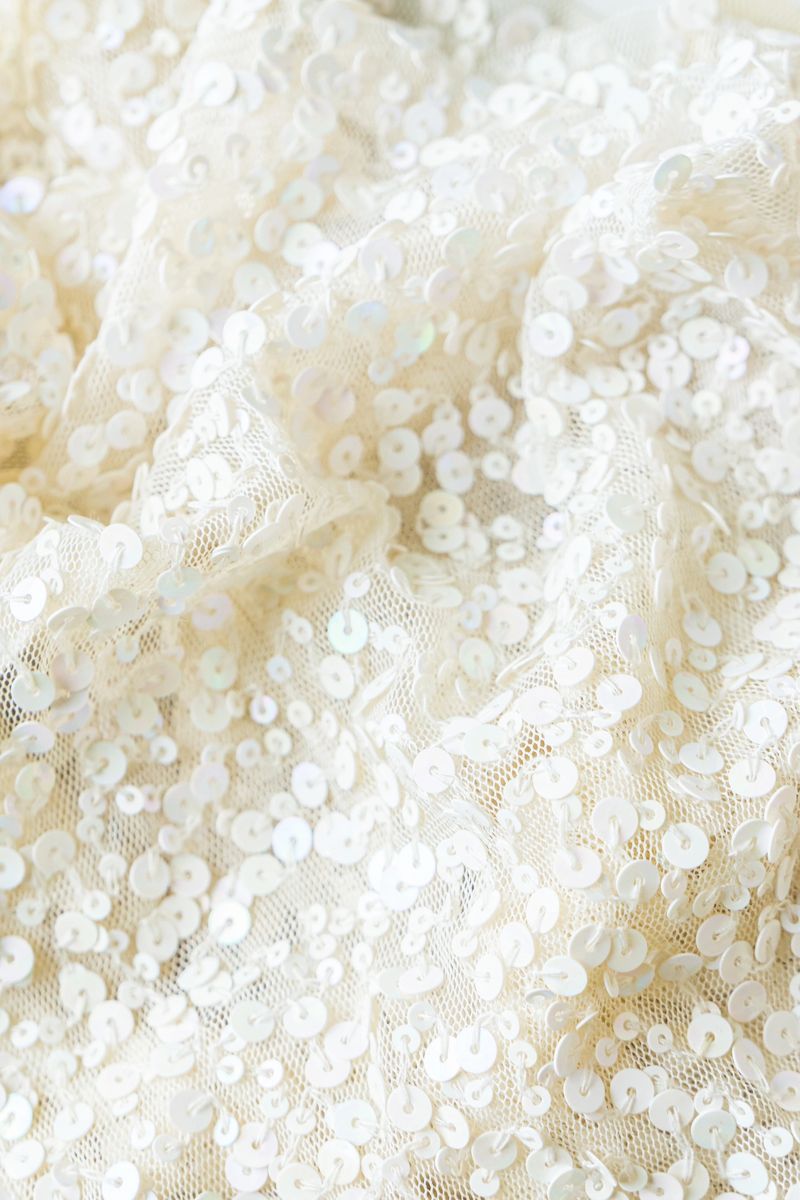 Close-up of a luxurious white sequined fabric, showcasing its intricate texture and delicate shimmer