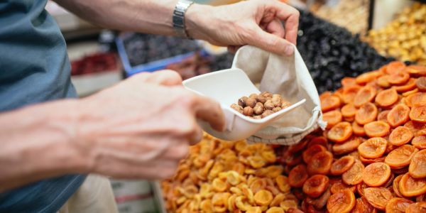 Person scooping dried nuts at a market.
