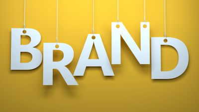 White letters spelling 'BRAND' hanging on strings against a yellow background.