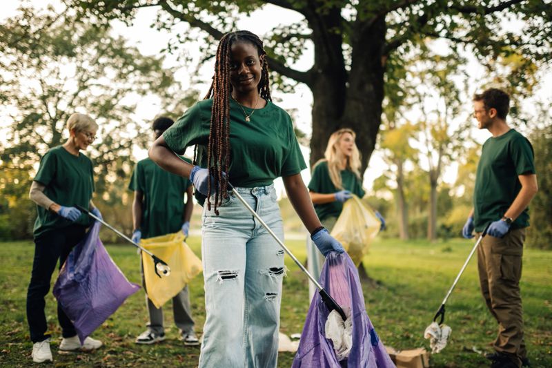 Diverse group of volunteers cleaning up trash in a public park, working together to protect the environment and promote sustainability