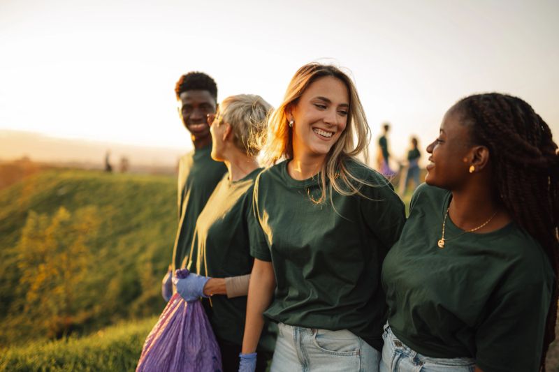 Volunteers are working together to pick up trash and make a difference in the environment. They are smiling and enjoying the experience of giving back to their community