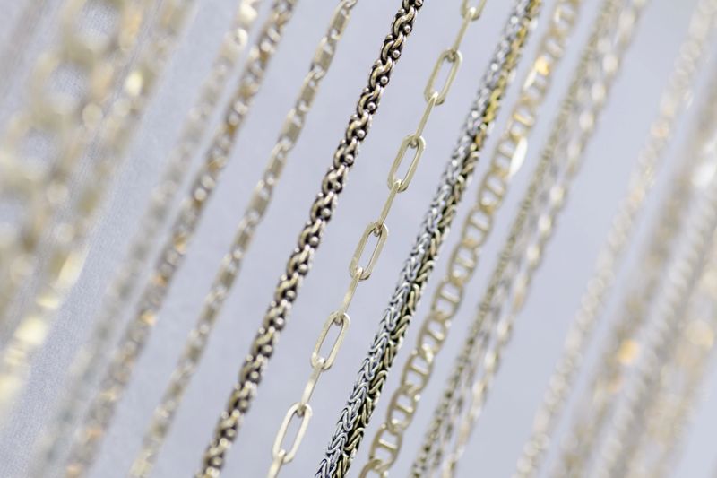 A large collection of silver chain necklaces elegantly displayed on a white jewelry stand