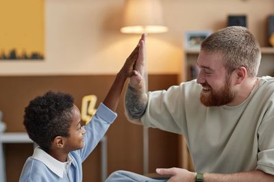 Image of a young male therapist smiling at a young male client. They are high fiving each other