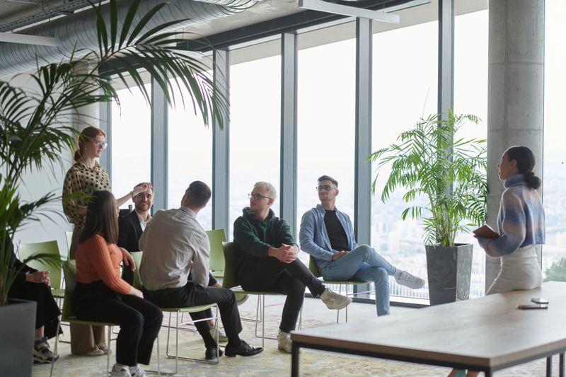 A diverse group of business professionals sits attentively in a modern office.