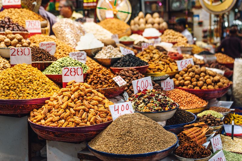 Captured in Chandni Chowk, the scene showcases various spices and grains vibrantly displayed in baskets, emphasizing the rich culture and liveliness of a traditional Indian marketplace.