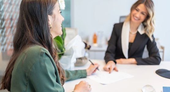 Two women engaging in a professional discussion across a desk.