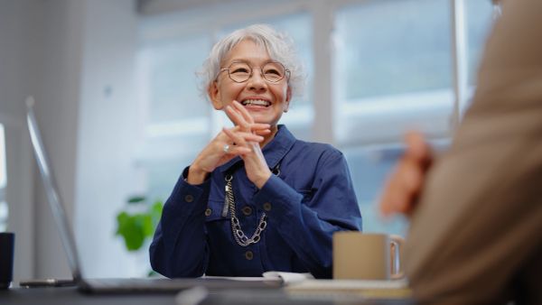 Elderly woman smiling and enjoying a conversation.