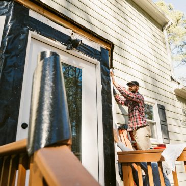Man installing insulation around a door on a house exterior.
