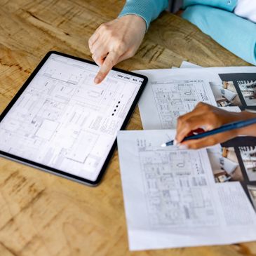 People reviewing architectural plans on paper and tablet.