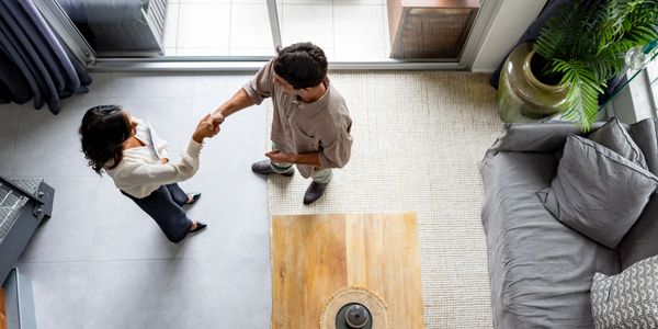 Two people shaking hands in a modern living room from a top view.