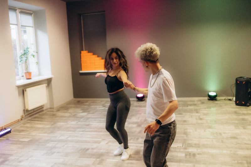 Positive young pair engaged in tango dance together with other attendees of dancing courses