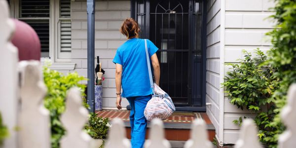 Healthcare worker entering a house.