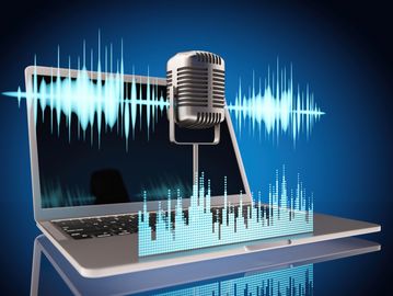 Retro microphone with digital sound waves above a laptop screen.