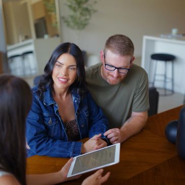 Couple consulting with a professional using a tablet.