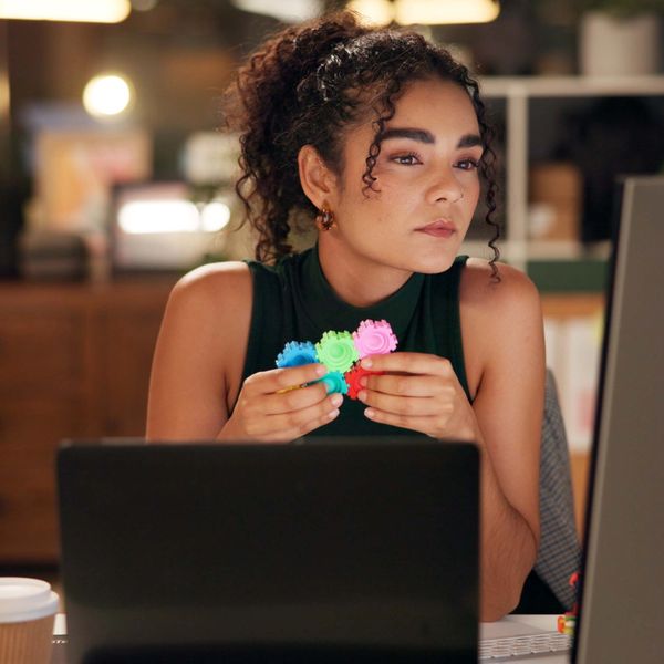 Woman concentrating while holding colorful gears at her desk.