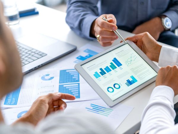 People analyzing data charts on a tablet and papers.