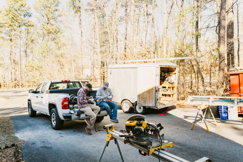 Construction workers sitting on pickup truck tailgate during lunch break