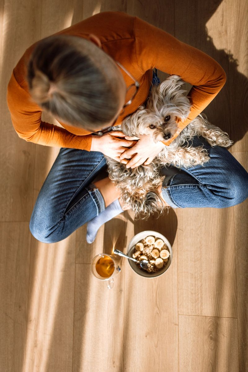 Photo of a smiling mid adult woman and her dog enjoying mornig sun in the living room