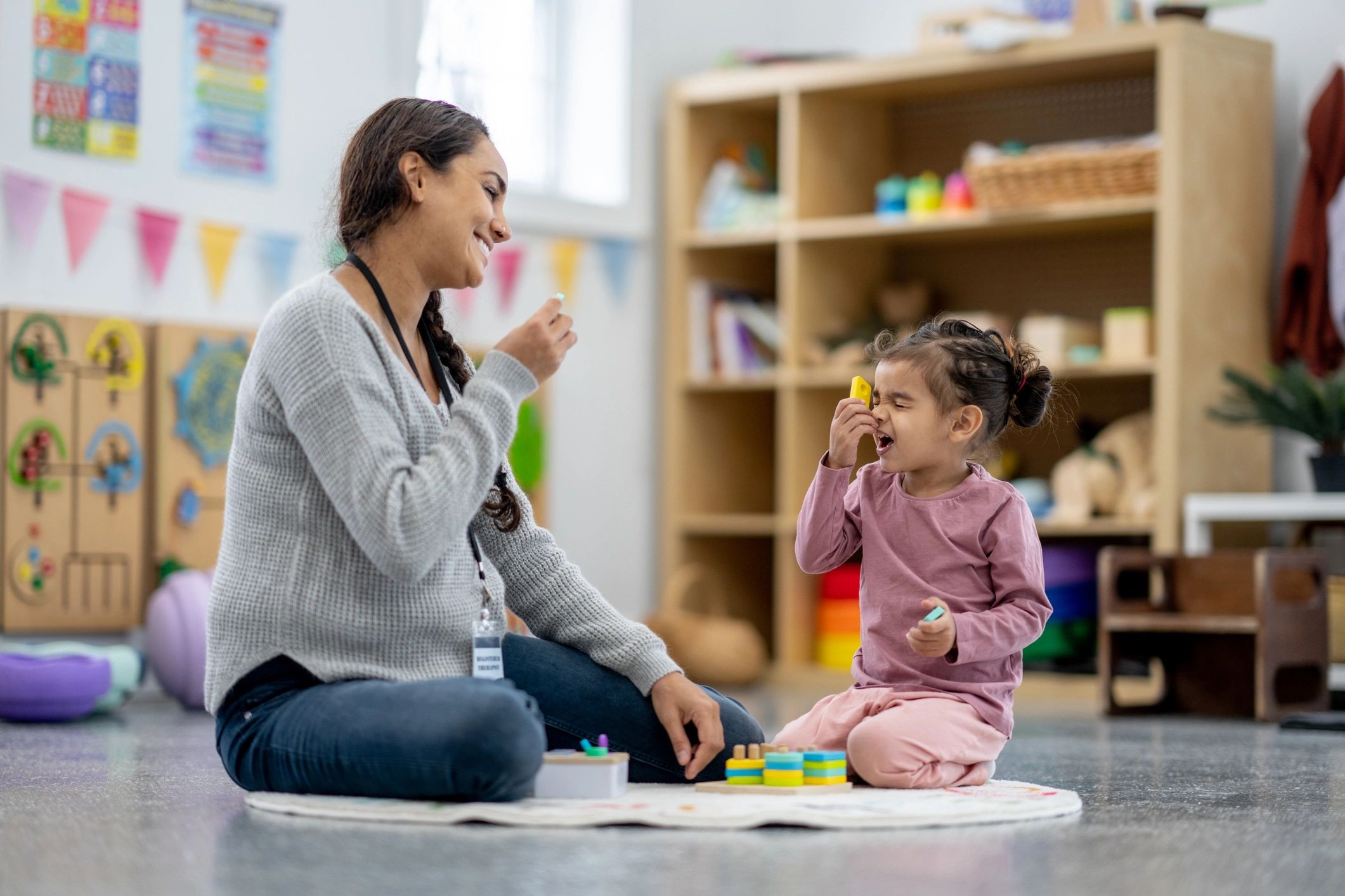 Therapist and child playing and smiling.