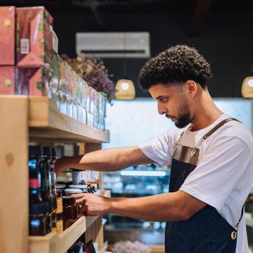 Man in apron stocking shelves in a store.