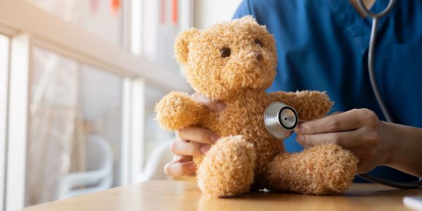 Doctor checking a teddy bear with a stethoscope.